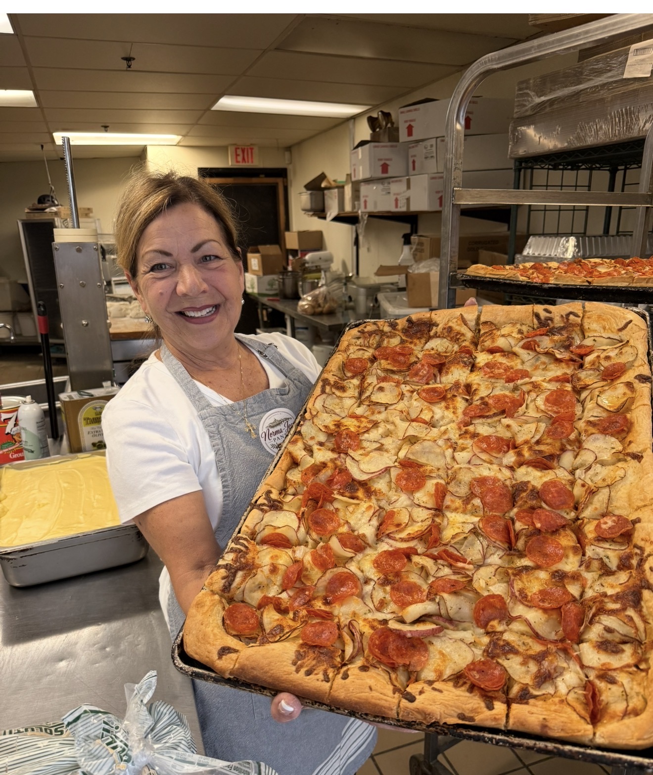 Norma-Jean smiling in the pantry with a freshly baked tray of pizza